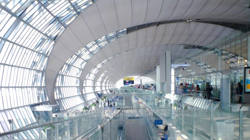 Spacious modern airport terminal with a curved glass roof, featuring bright interiors and walkways.